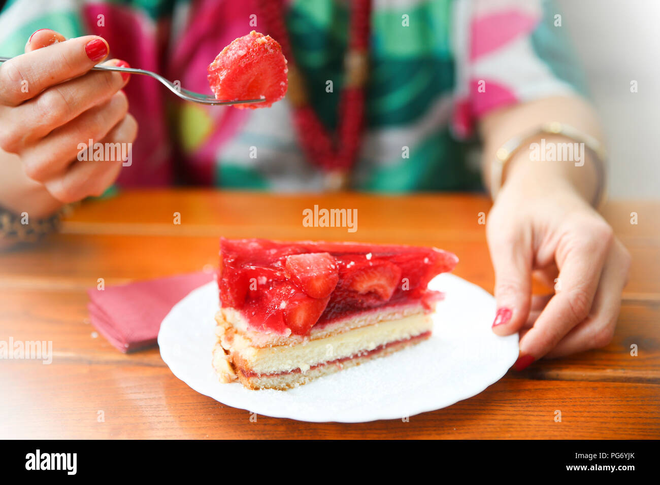 Close-up di donna di mangiare la torta di fragole in street cafe Foto Stock