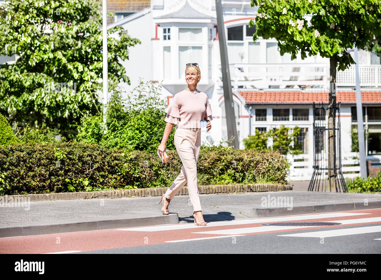 Donna sorridente di attraversare una via Foto Stock