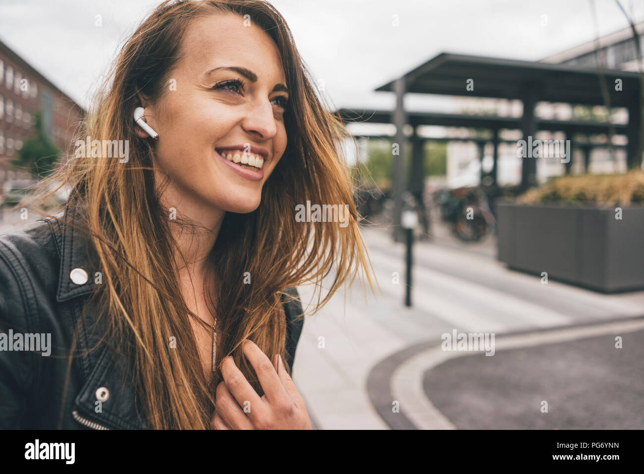 Sorridente giovane donna indossa auricolari consentono di Foto Stock