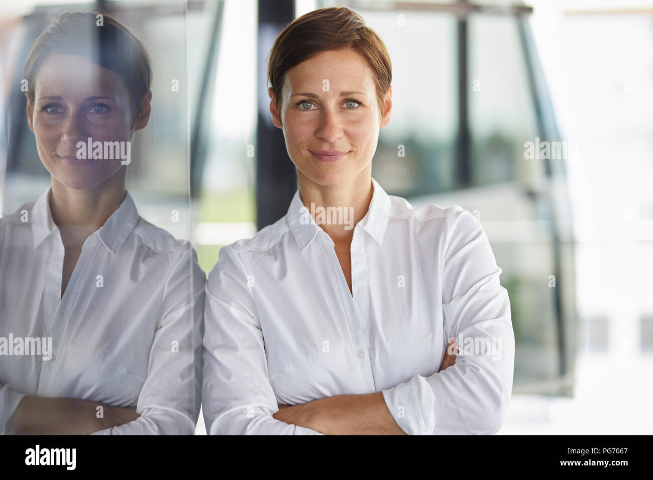 Ritratto di sorridere imprenditrice appoggiata al vetro in office Foto Stock