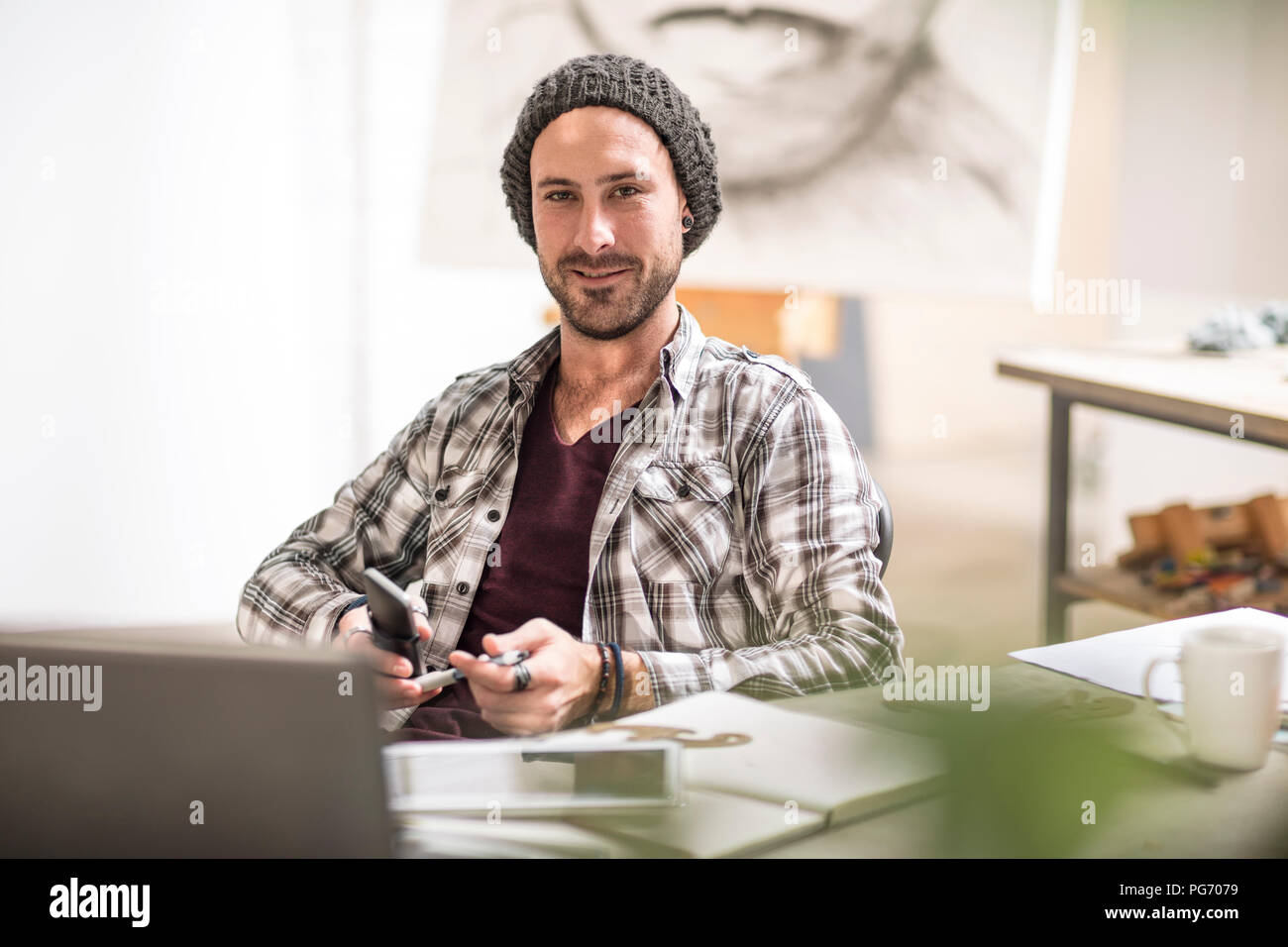 Ritratto di fiducioso artista seduto alla sua scrivania in studio Foto Stock