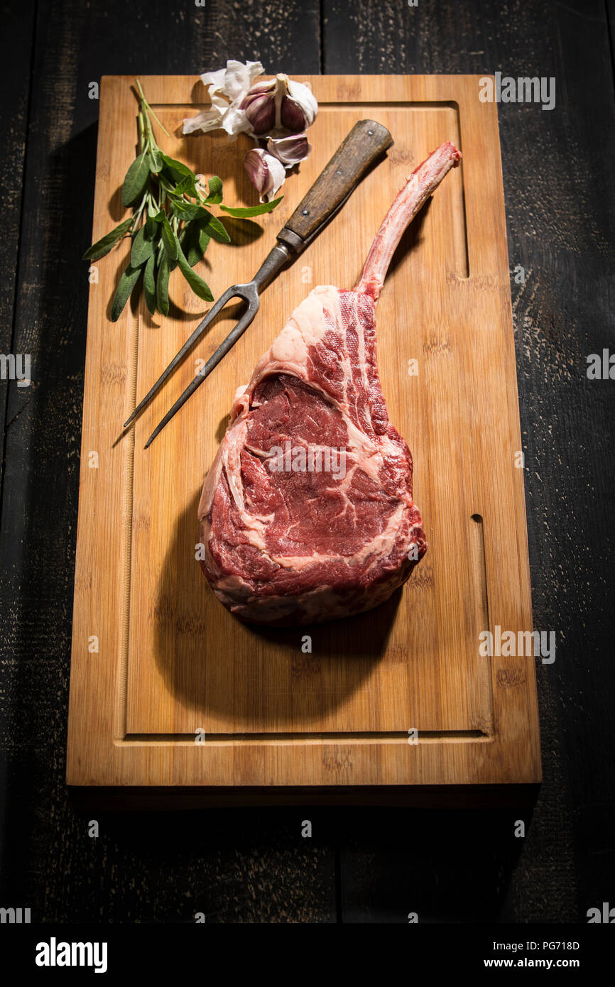 Materie tomahawk bistecca, aglio ed erbe aromatiche Foto Stock