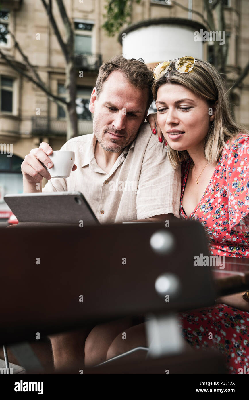 Giovane guardando il tablet ad un cafe' all'aperto Foto Stock