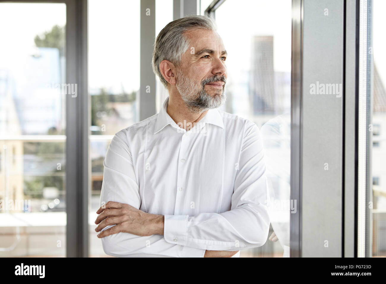 Ritratto di imprenditore sorridente guardando fuori della finestra Foto Stock