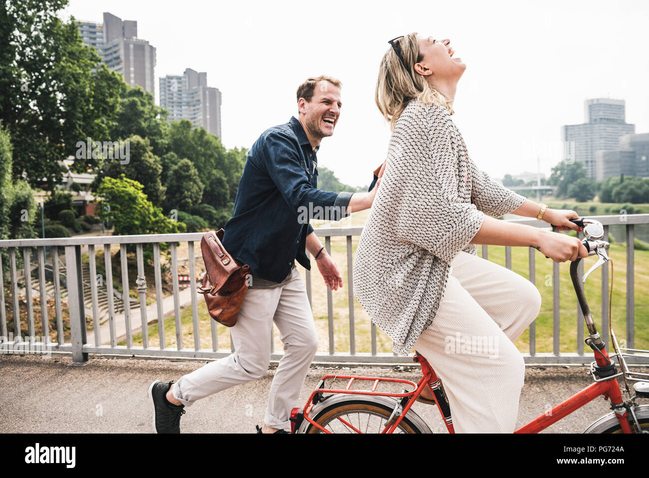 Coppia felice attraversando un ponte con la bicicletta e a piedi Foto Stock