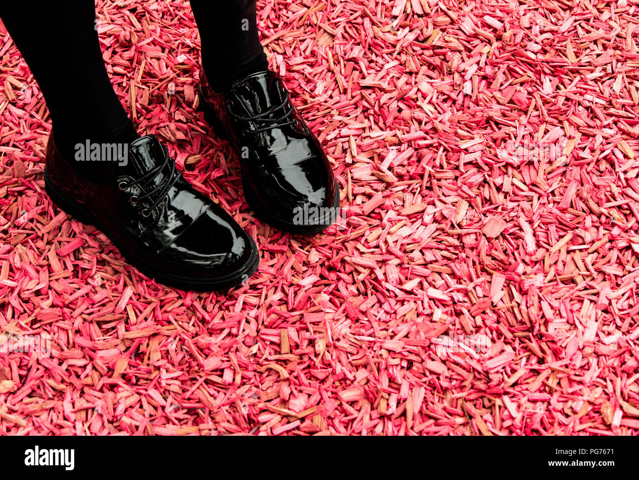La ragazza lucido nero scarpe rosa sul terreno di truciolo Foto Stock