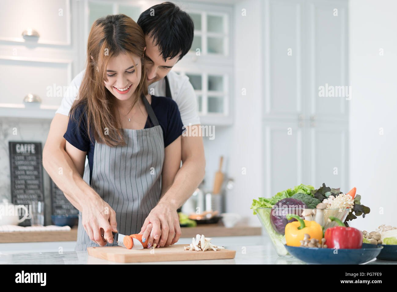 Giovane bella giovane in cucina. Famiglia di due nella preparazione degli alimenti. Giovane rendendo deliziosa insalata. La cottura di hobby il concetto di stile di vita. Foto Stock