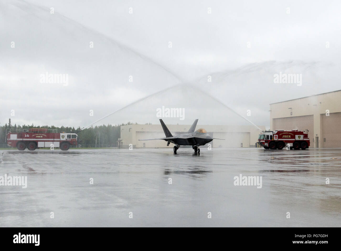 Air Force Lt. Gen. Ken Wilsbach ottiene un cerimoniale di acqua salutare nel suo F-22 Raptor durante il suo ultimo volo come comandante del Comando in Alaska, Alaskan North American Aerospace Defense Regione e undicesimo Air Force, a base comune Elmendorf-Richardson, Alaska, 20 Agosto, 2018. Wilsbach è un comando pilota con più di 5.000 ore di volo, principalmente in F-15C, MC-12 e F-22, e ha volato 71 missioni di combattimento in operazioni nord guarda, guarda a sud ed Enduring Freedom. (U.S. Air Force foto di Alejandro Peña) Foto Stock