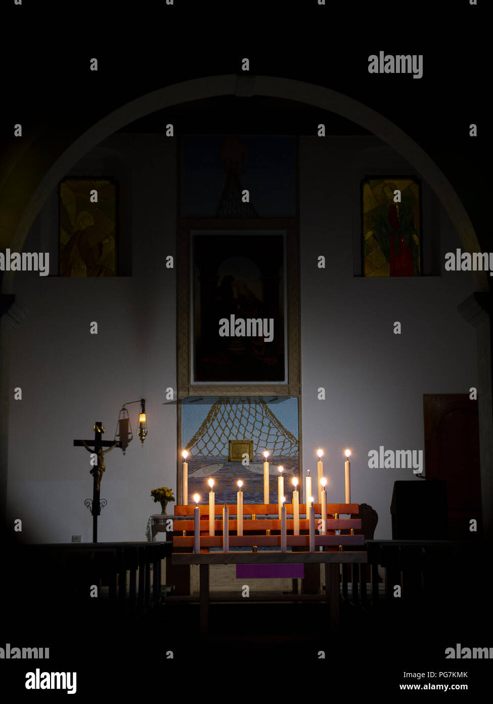 Semi-buio interiore di una piccola chiesa cattolica, illuminate solo a lume di candela in un Villaggio in Calabria (Italia) Foto Stock