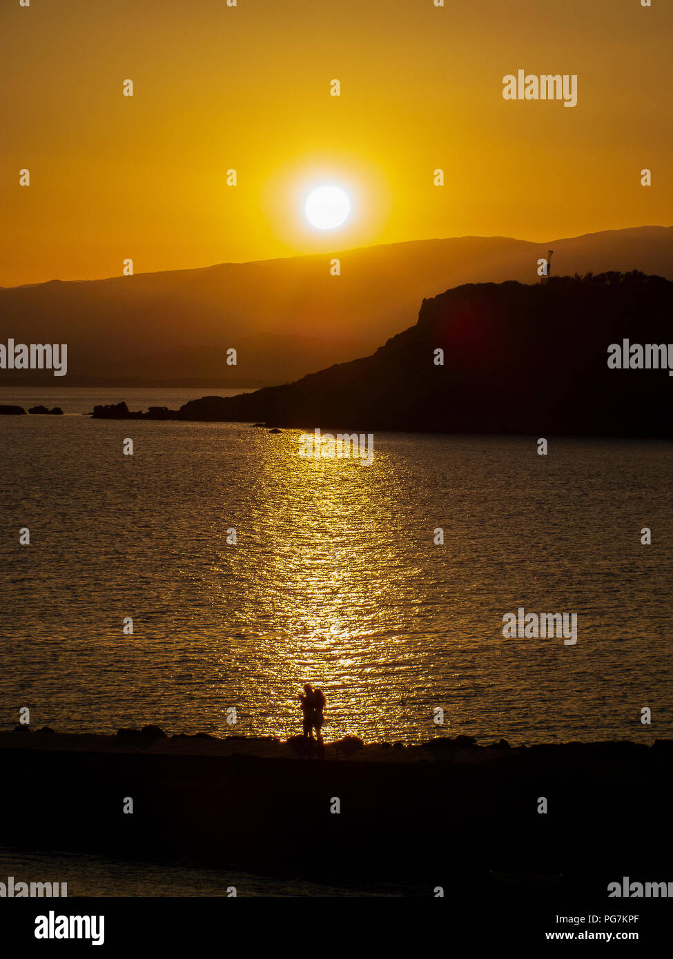 Bellissimo e romantico tramonto d'estate, nella retroilluminazione del mare calabrese, con il promontorio in background Foto Stock