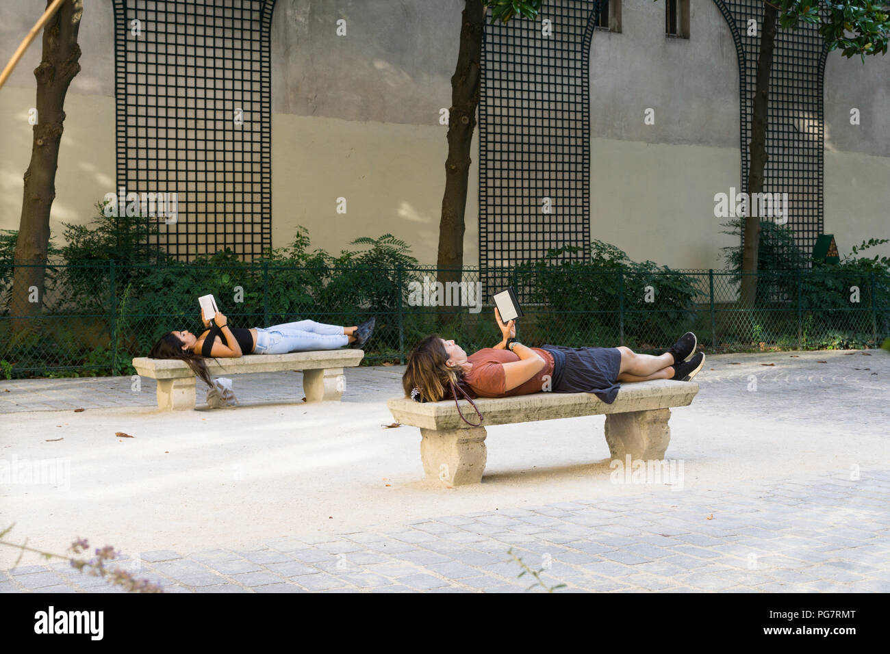 La lettura del libro nel parco - Due donne sdraiati sulle panchine, la lettura di libri a Parigi, in Francia, in Europa. Foto Stock