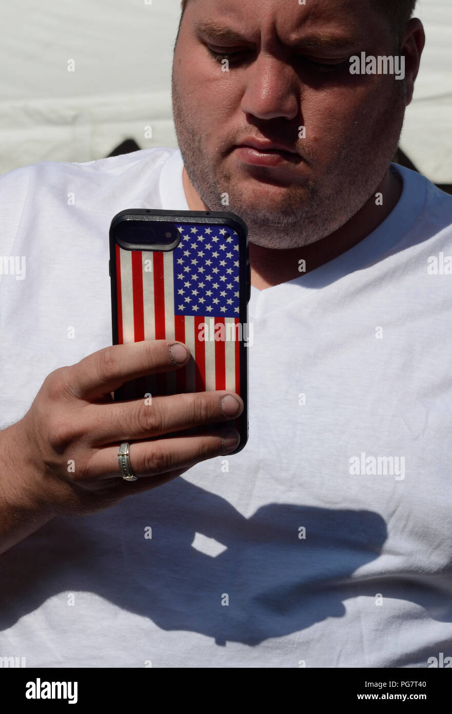 Un uomo che usa il suo smartphone con una bandiera americana caso. Foto Stock