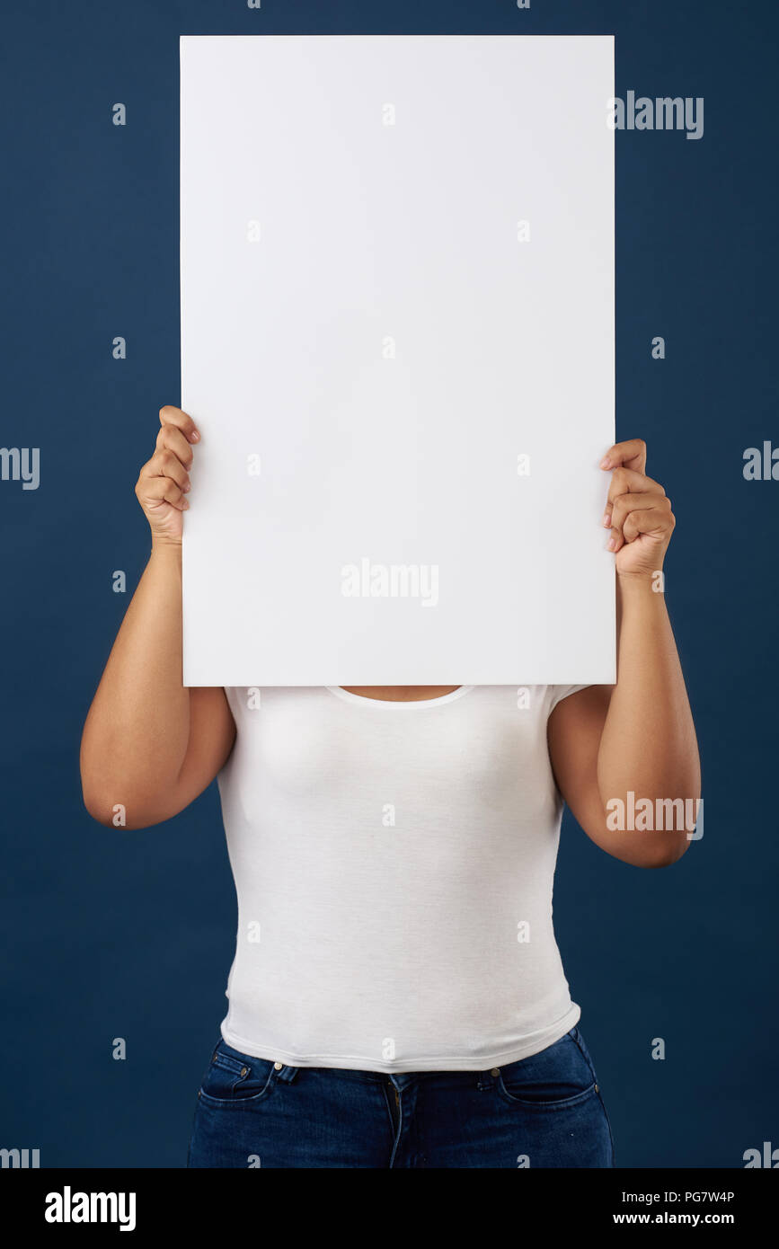 Donna nascondere il viso con banner bianco isolato su blu di sfondo per studio Foto Stock
