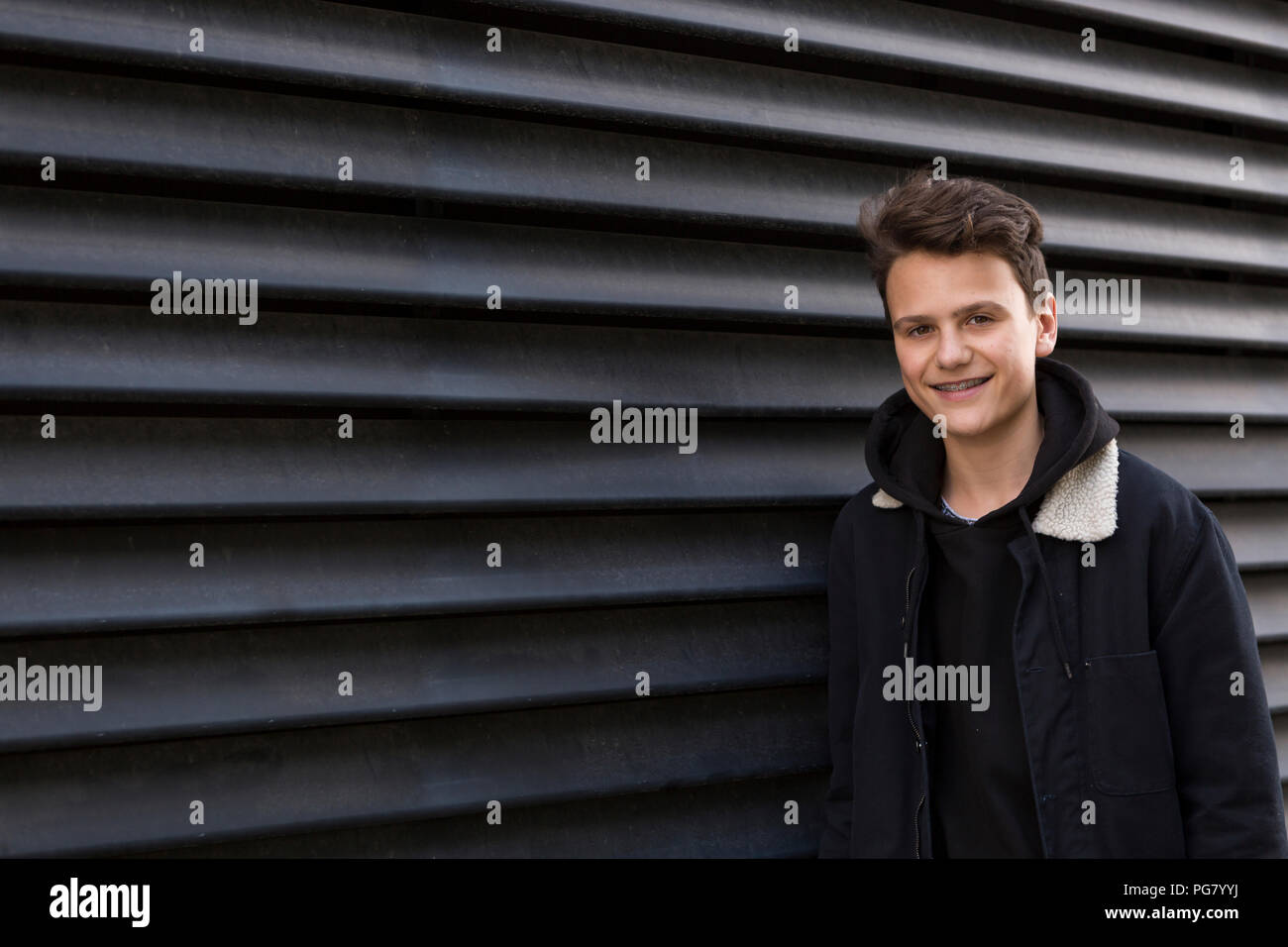 Ritratto di sorridere ragazzo adolescente su sfondo nero Foto Stock