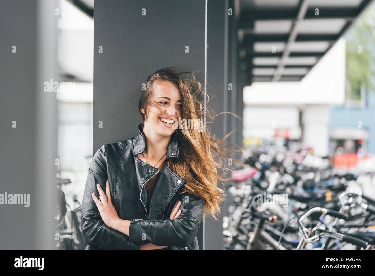 Ritratto di felice giovane donna presso il parcheggio per le bici in stazione in città Foto Stock