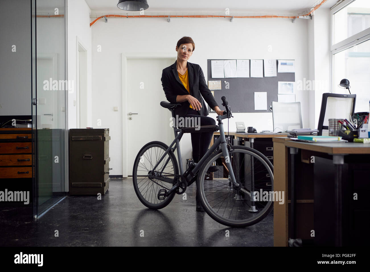 Imprenditrice con bicicletta nella sua azienda start-up Foto Stock