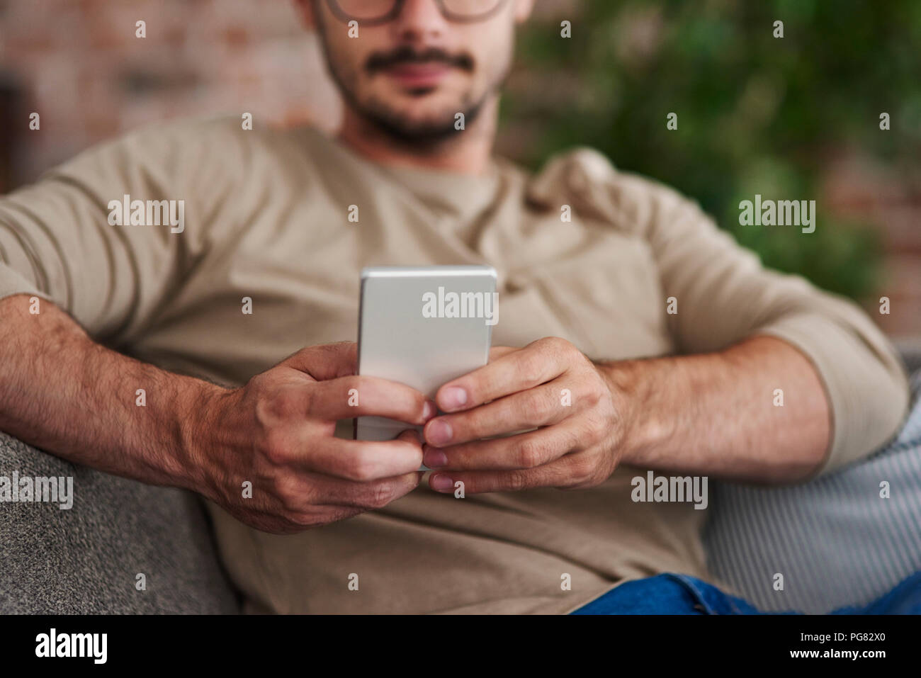 Uomo seduto sul lettino della messaggistica di testo, vista parziale Foto Stock
