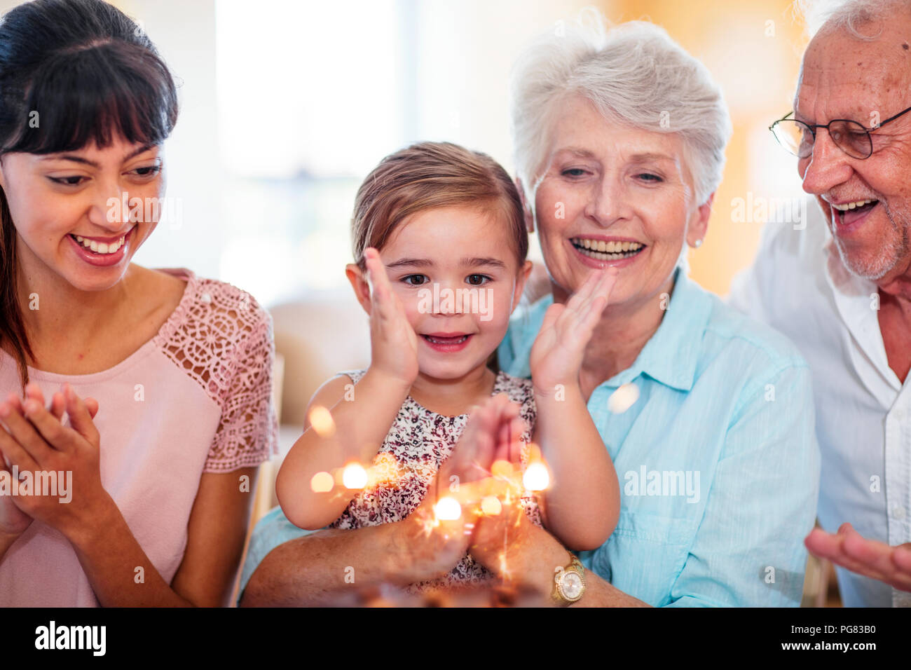 Bambina lwatching botti su una torta di compleanno, seduti su una nonna lap Foto Stock