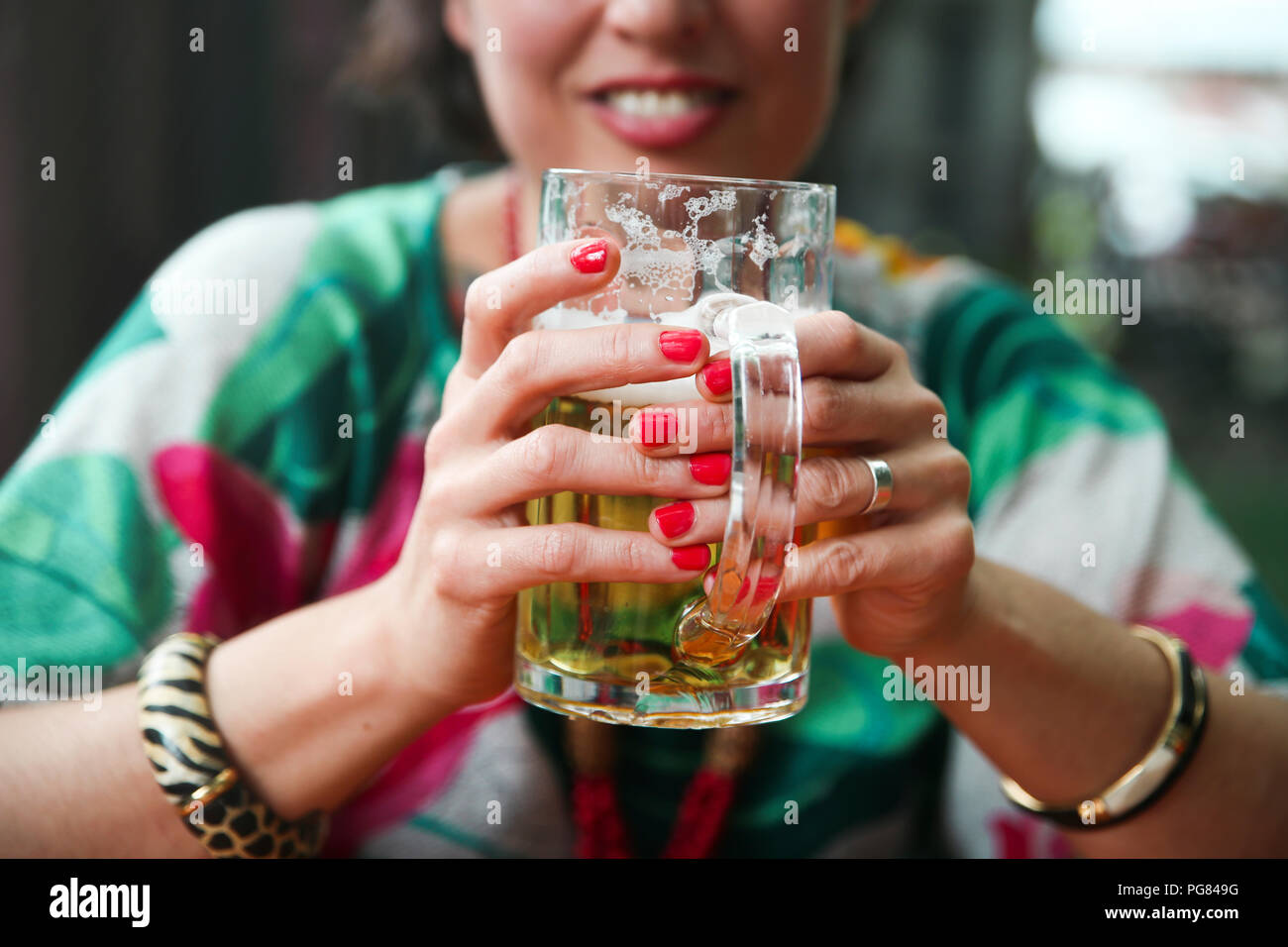 Close-up di donna tenendo un boccale di birra in un ristorante di strada Foto Stock