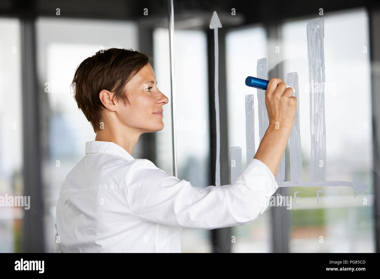 Imprenditrice disegno grafico a barre nella lastra di vetro in office Foto Stock