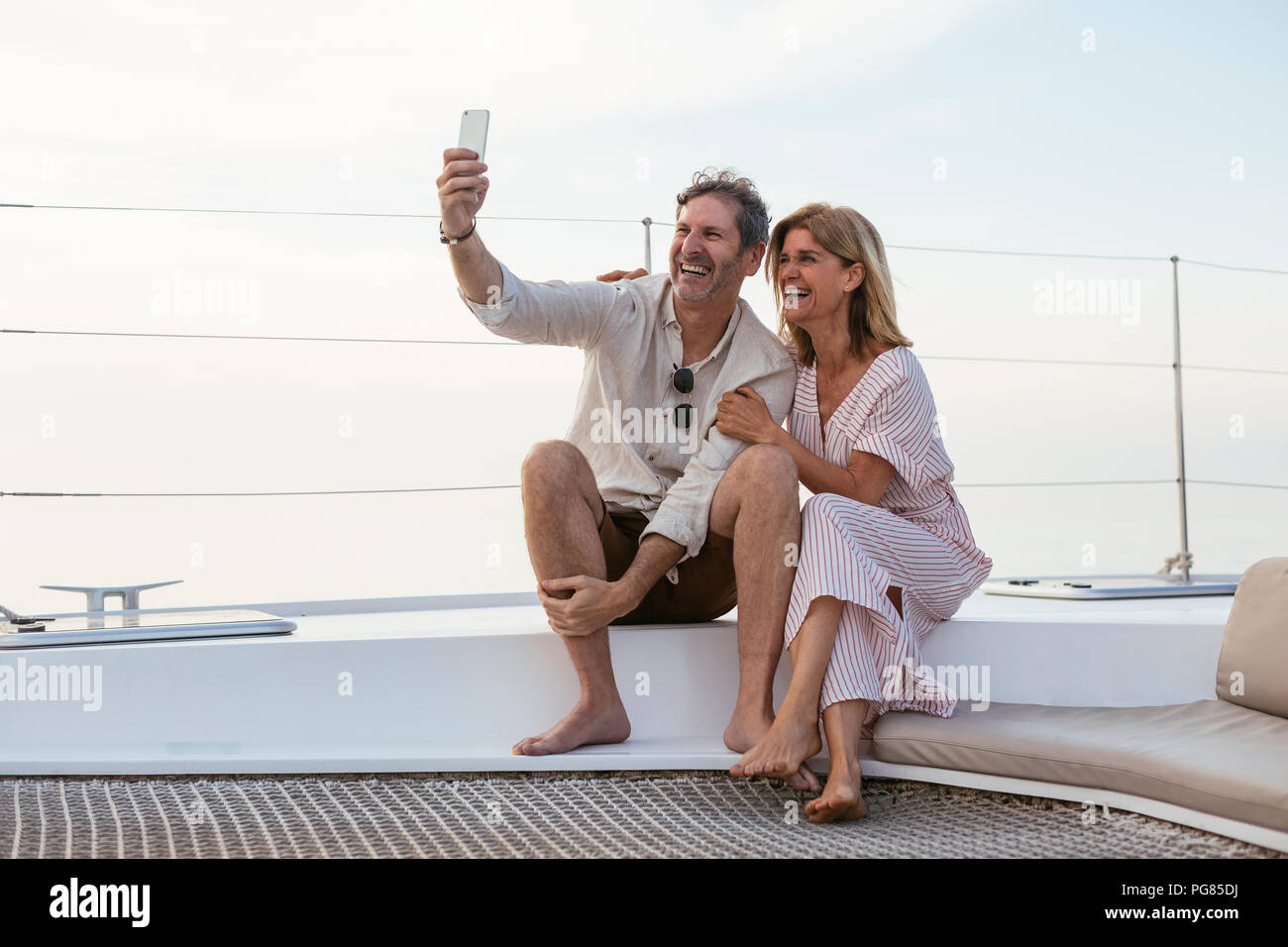 Coppia felice su un viaggio in barca a vela tenendo selfies Foto Stock