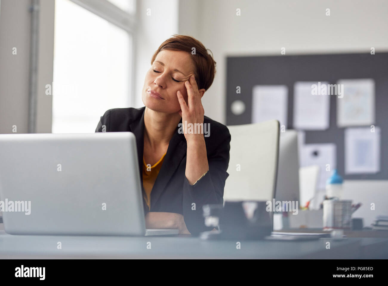 Imprenditrice seduta in ufficio, con un mal di testa Foto Stock