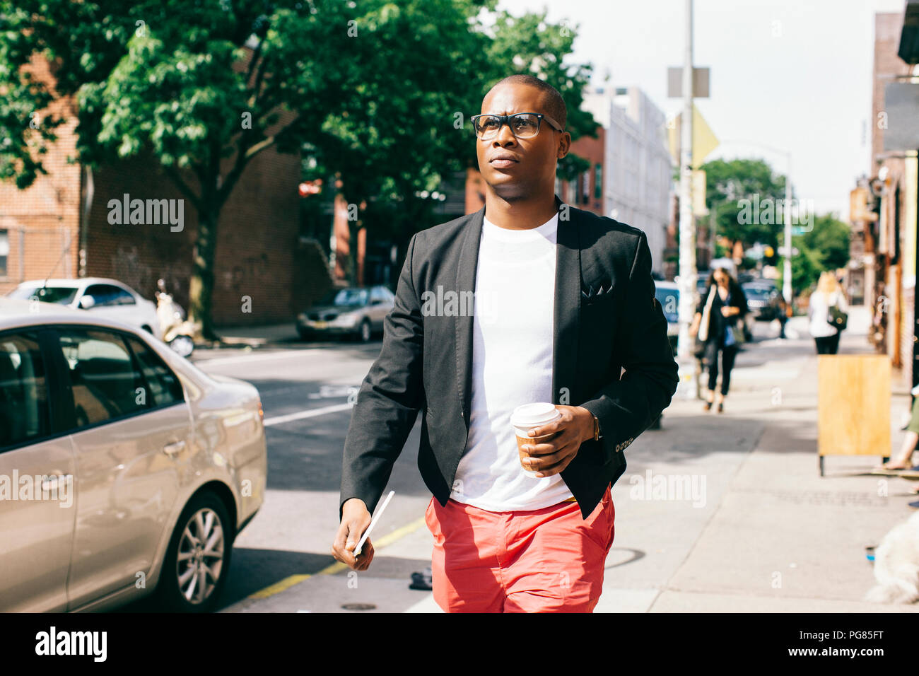 Stati Uniti d'America, New York, Brooklyn, uomo a camminare per la strada, tenendo tazza di caffè Foto Stock