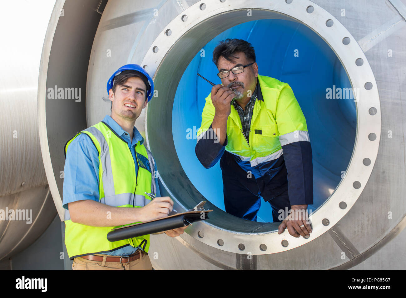 Due lavoratori a un serbatoio di appunti e walkie-talkie Foto Stock