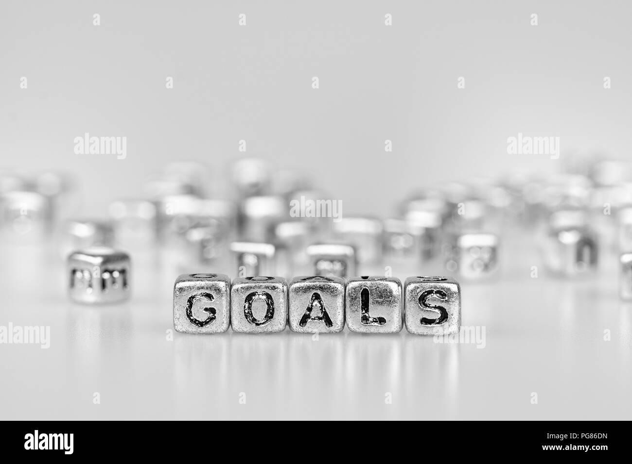 Obiettivi parola scritta sul cubo di argento con il bianco e nero bokeh cube parola sullo sfondo del blocco Foto Stock