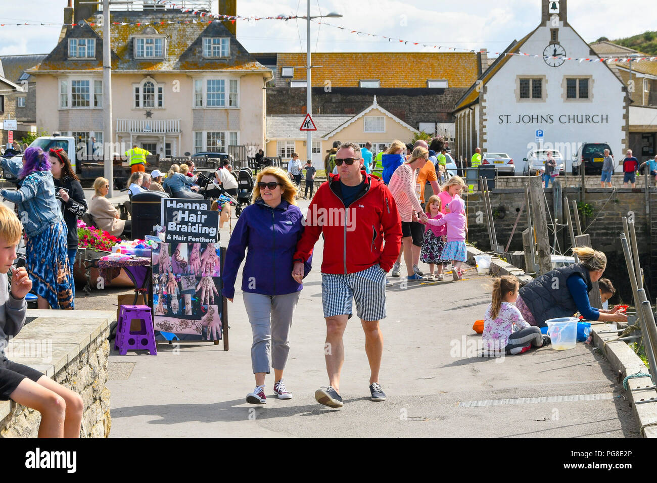 West Bay, Dorset, Regno Unito. 24 agosto 2018. Regno Unito Meteo. I villeggianti avvolto in abiti caldi alla stazione balneare di West Bay nel Dorset dopo le temperature hanno preso una drammatica caduta dopo un fronte freddo passata attraverso portando i climi freddi dall'artico in vista del weekend. Credito Foto: Graham Hunt/Alamy Live News Foto Stock