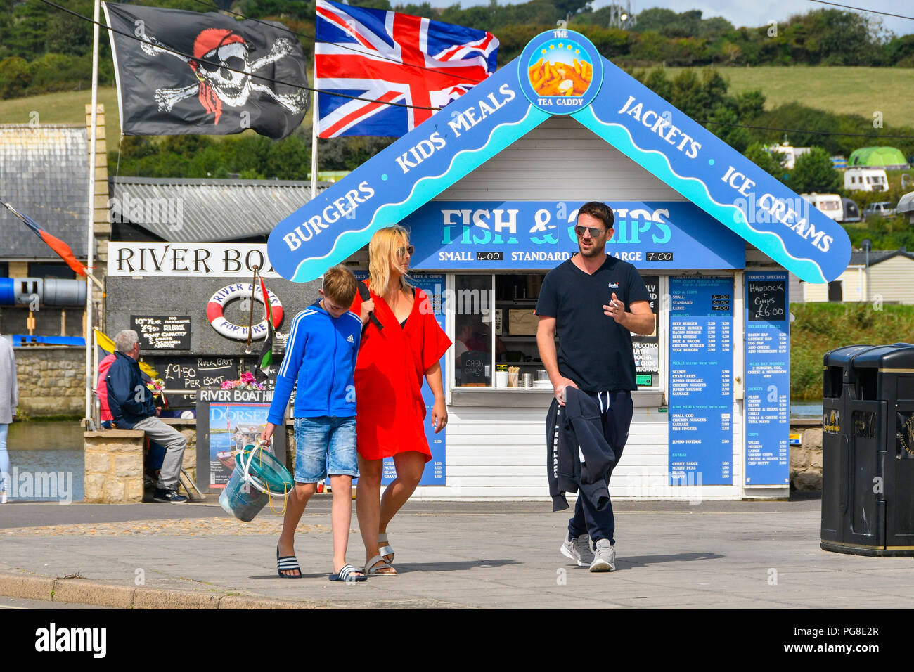 West Bay, Dorset, Regno Unito. 24 agosto 2018. Regno Unito Meteo. I villeggianti avvolto in abiti caldi alla stazione balneare di West Bay nel Dorset dopo le temperature hanno preso una drammatica caduta dopo un fronte freddo passata attraverso portando i climi freddi dall'artico in vista del weekend. Credito Foto: Graham Hunt/Alamy Live News Foto Stock