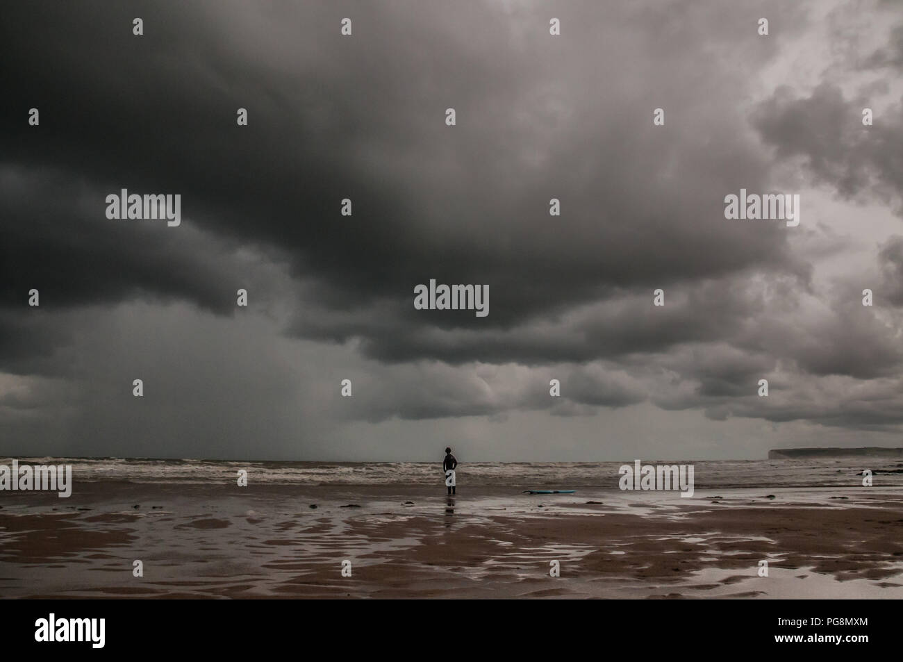 Birling Gap, East Sussex, Regno Unito, 24 Agosto 2018. Tempo del Regno Unito: Un cambiamento drammatico nel tempo, in quanto il forte vento di Westerley porta nuvole scure e pioggia sulla costa meridionale. Surfer sondaggio la scena. Foto Stock