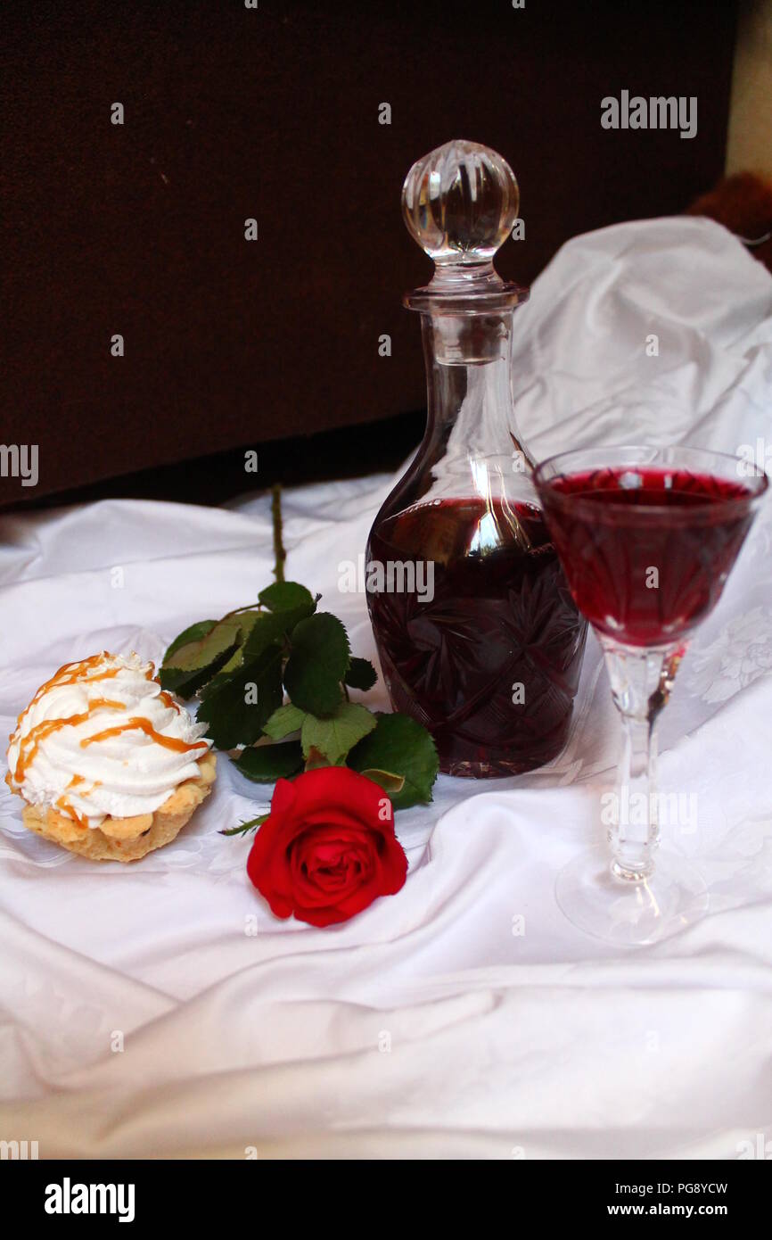 Crema leggera torta con rose rosse e il profumo del vino rosso in vetro per il bel regalo o un romantico dessert Foto Stock