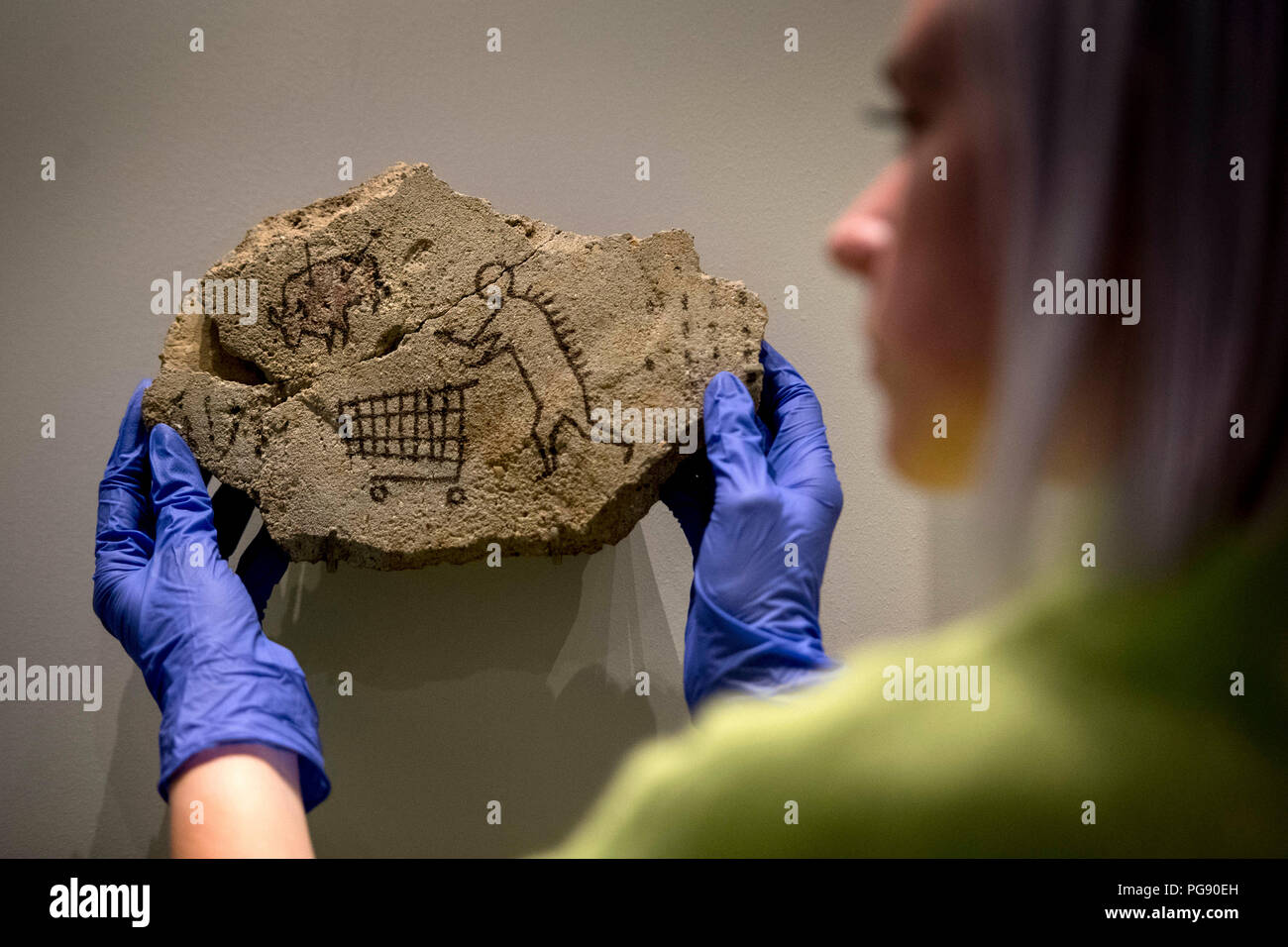 Harriet McColm del team delle collezioni del British Museum prepara il Peckham Rock di Banksy prima dell'installazione al British Museum di Londra. L'artista ha collocato segretamente il pezzo storico mock in una galleria al museo nel 2005, quando è andato inosservato per tre giorni, e ora sta ritornando con il permesso come parte della mostra curata di Ian Hislop 'i object: Ricerca di Ian Hislop per dissenso. Foto Stock