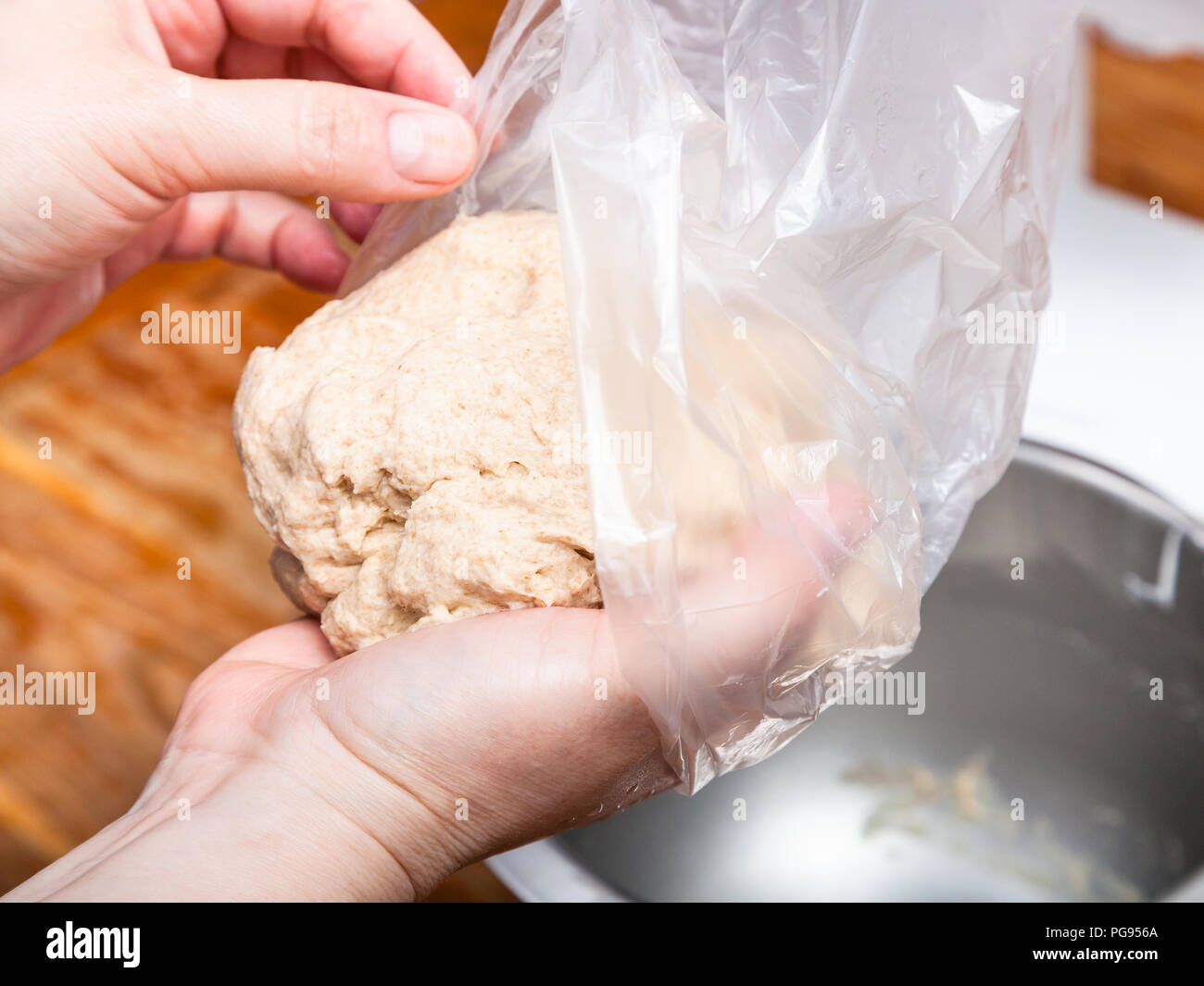 La cottura della torta - mani mettere la palla di pasta in un sacchetto di plastica Foto Stock