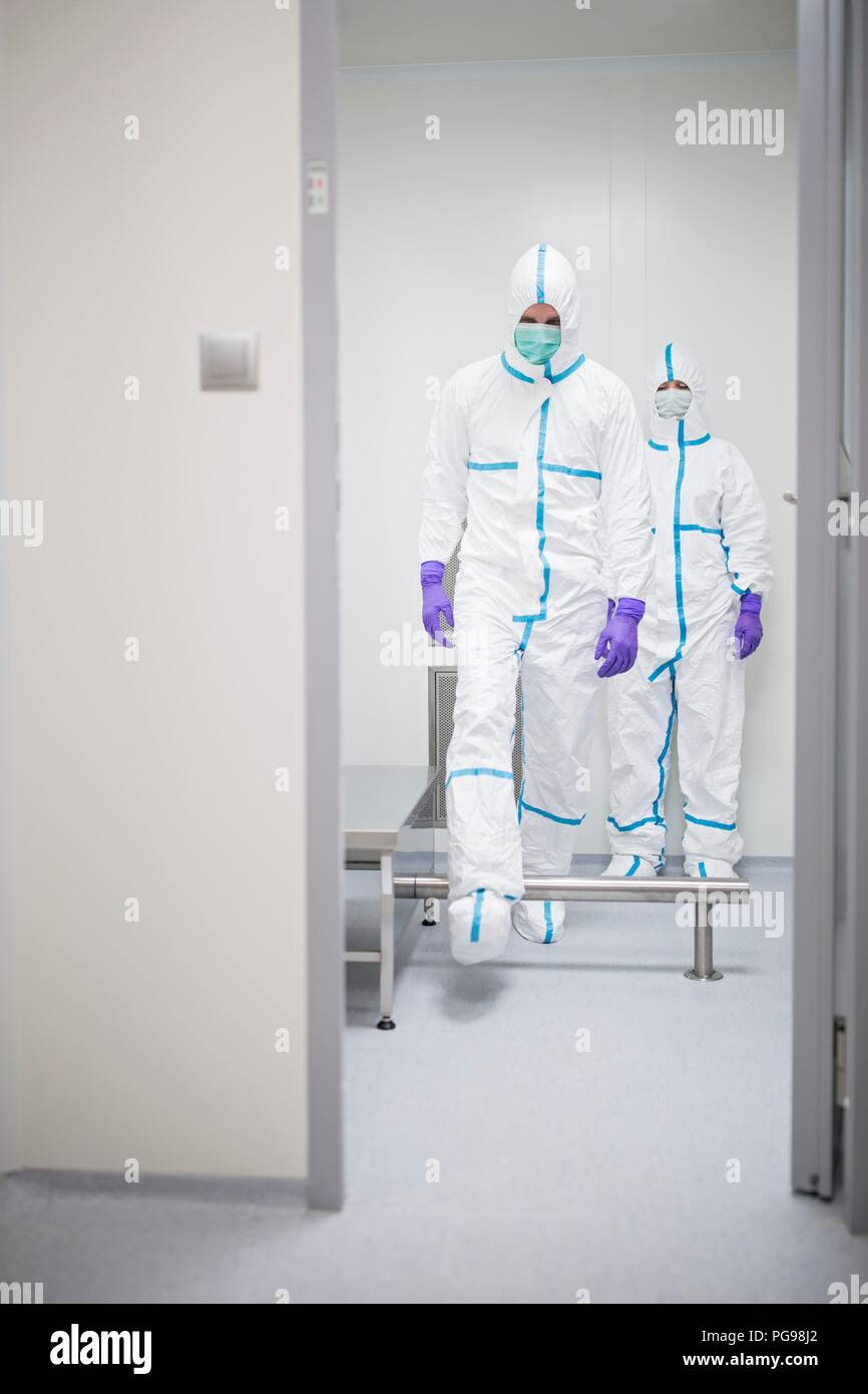 I tecnici a piedi attraverso una cabina di decontaminazione prima di entrare in un laboratorio sterile. Foto Stock