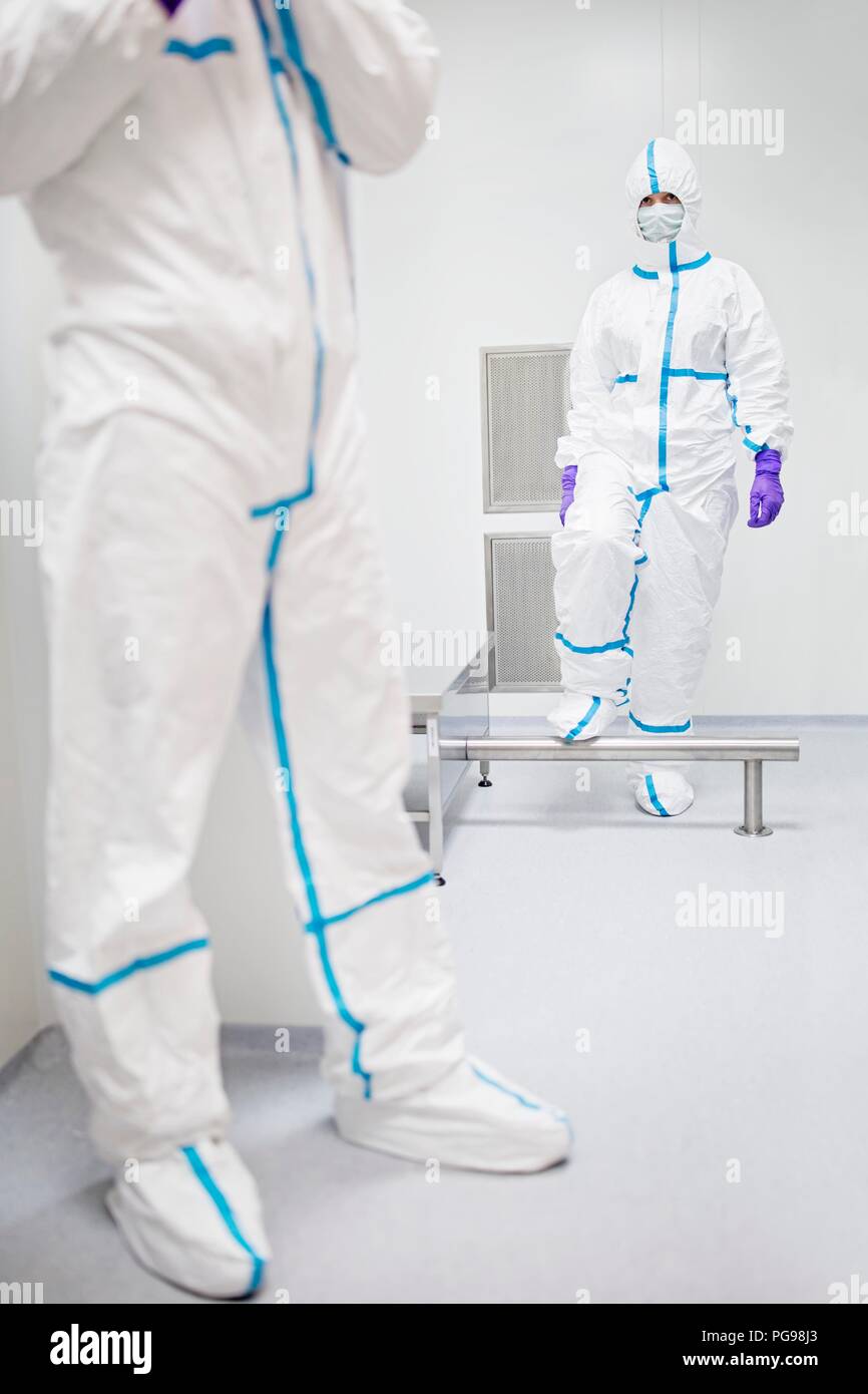 I tecnici a piedi attraverso una cabina di decontaminazione prima di entrare in un laboratorio sterile. Foto Stock