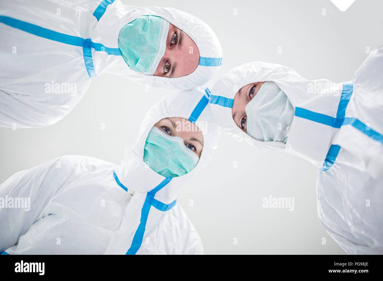 Tecnici di laboratorio indossando tute protettive e maschere facciali in un laboratorio che deve mantenere un ambiente sterile. Foto Stock