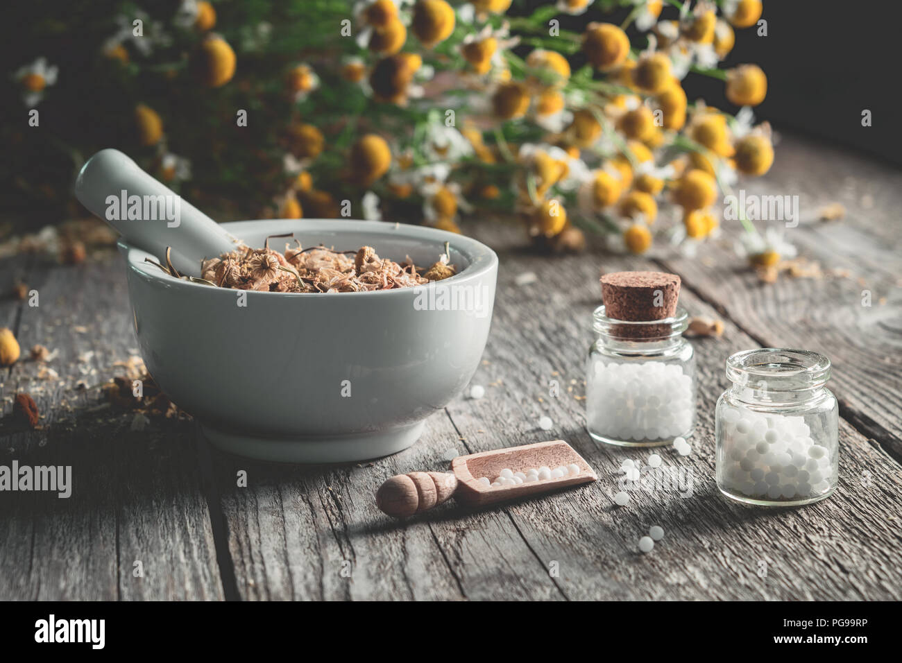 La malta di essiccato alle erbe curative, globuli omeopatici e il mazzetto di piante di camomilla. L'omeopatia e la medicina di erbe. Foto Stock