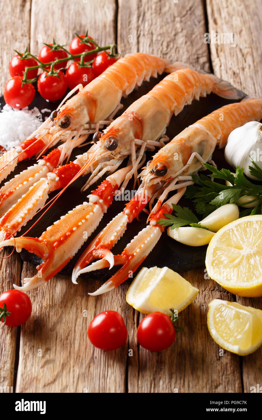 Crudo fresco di scampi, la baia di Dublino boreale, gli scampi con limone, aglio, pomodori, erbe aromatiche e spezie da vicino sul piano verticale. Foto Stock