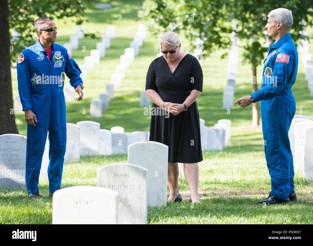 L'astronauta della NASA Joe Acaba, sinistra e Mark Vande Hei, destra, guarda come Julie Vande Hei, moglie di Mark, prende un momento dopo il posizionamento di un fiore presso il recinto di ex astronauta e U.S. Il senatore John Glenn, Venerdì, 15 giugno 2018 presso il Cimitero di Arlington in Arlington, Virginia Foto Stock