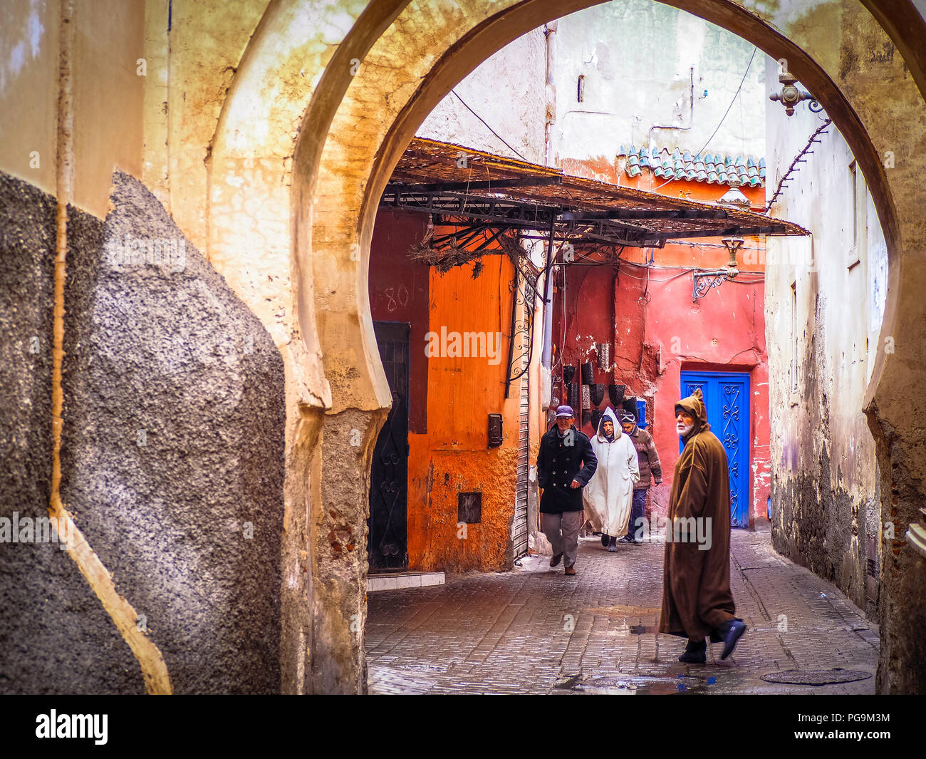 Uomo locale indossando il tradizionale abbigliamento marocchino a camminare lungo un vicolo Foto Stock