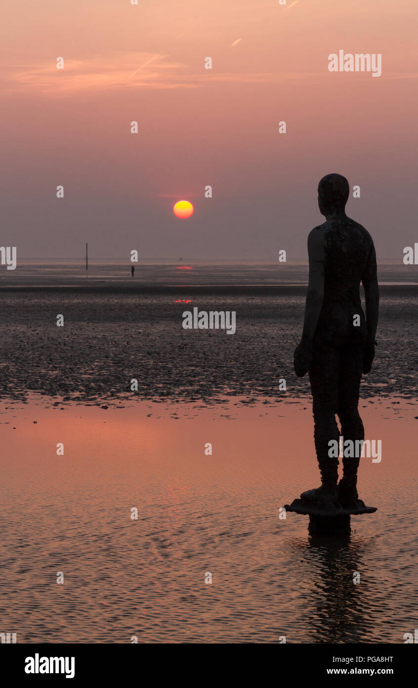 Antony Gormley statue stand in attesa su Crosby Beach per la marea per eseguire il rollback a. Foto Stock