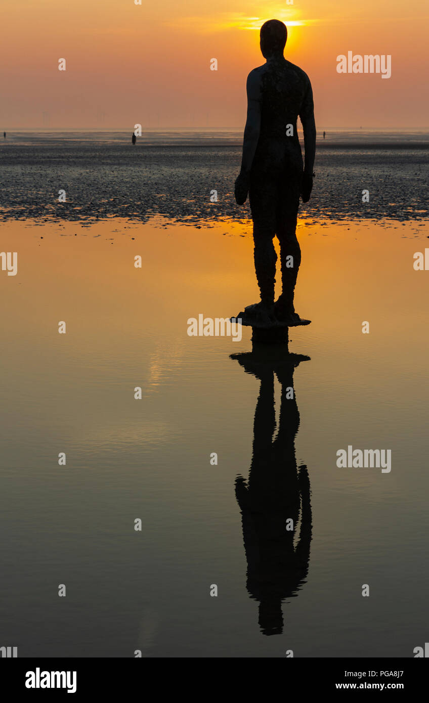 Antony Gormley statue stand in attesa su Crosby Beach per la marea per eseguire il rollback a. Foto Stock
