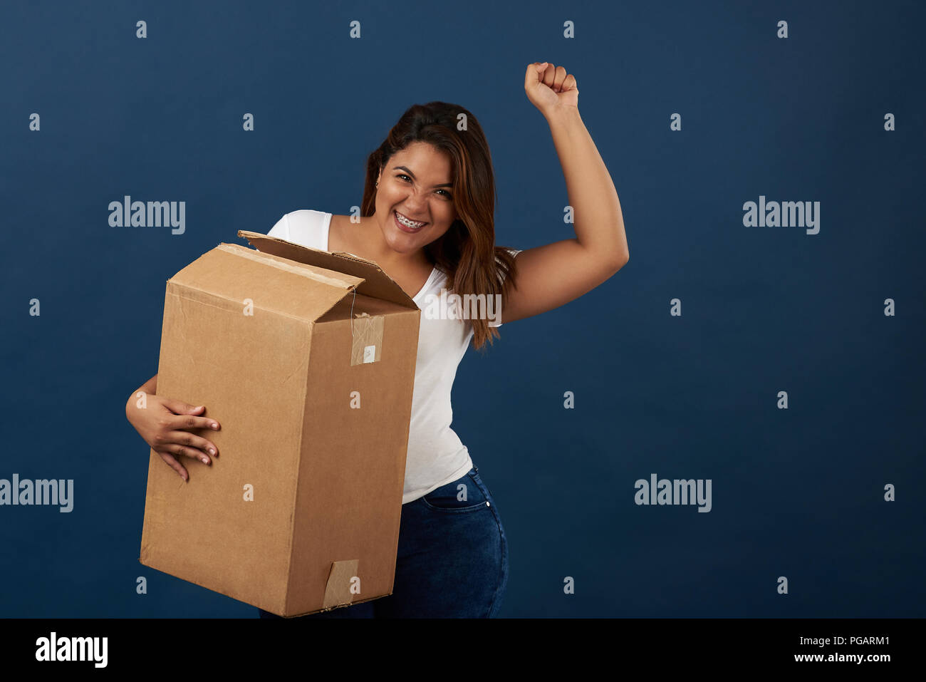 Donna felice con scatola isolata sul blu di sfondo per studio Foto Stock
