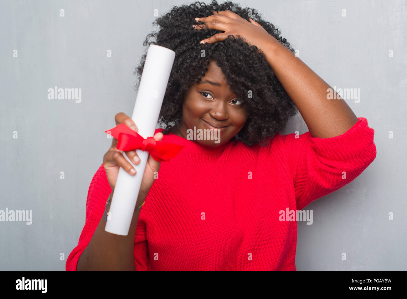 Giovane africano donna americana su grigio parete grunge holding diploma ha sottolineato con la mano sulla testa, sconvolto con vergogna e la sorpresa di fronte, arrabbiato e frustra Foto Stock