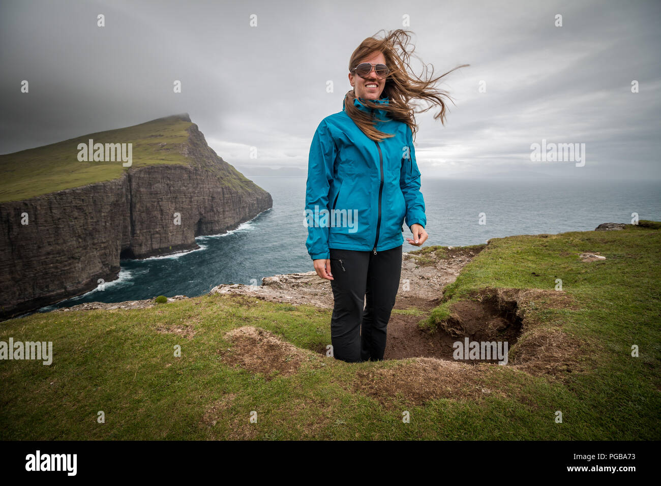 Felice giovane donna capelli piegando nel vento di viaggio il concetto di stile di vita, Traelanípa scogliere, Isola di Vágar, Isole Faerøer Foto Stock