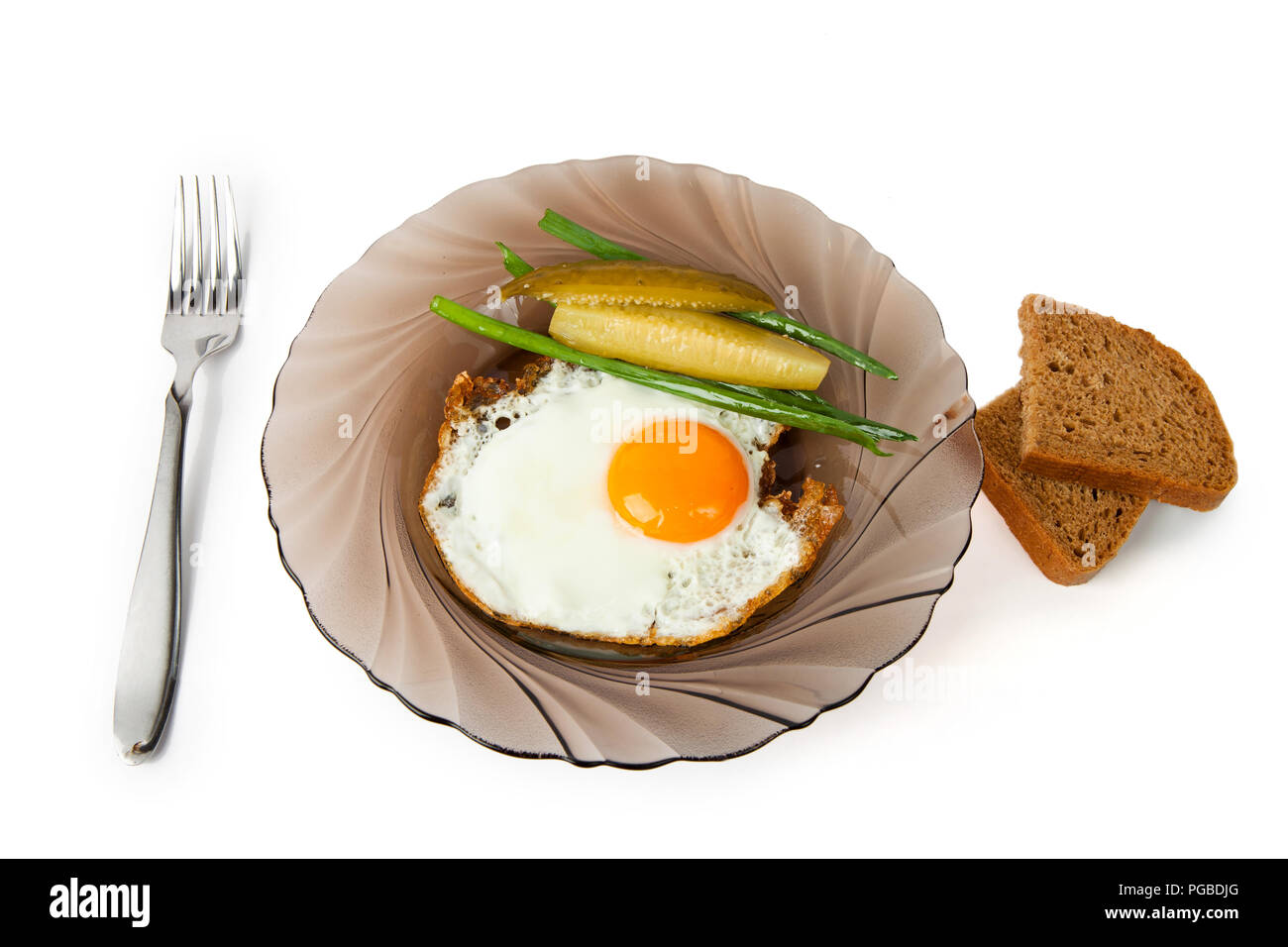 La colazione uova fritte su una lastra di vetro con un cetriolo marinaded, cipolle fresche e pane di segale Foto Stock