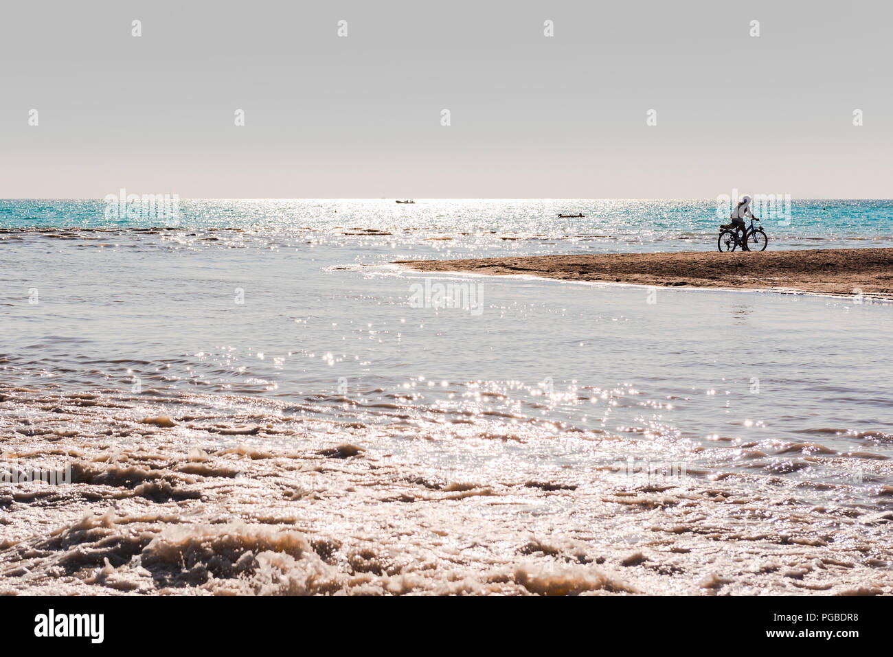 La silhouette di un ciclista solitario sulla spiaggia di Cecina, in Toscana Foto Stock