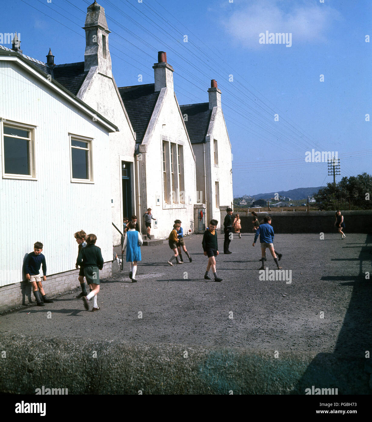 Anni sessanta, i bambini al di fuori della loro scuola nel parco giochi, a Lochboisdale, sull'Isola di South Uist ,nelle Ebridi Esterne, Scozia. Foto Stock